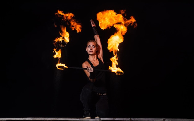 Высокоэнергетическая танцовщица огня Чувственная танцовщица огня крутит пылающую дубинку в темноте Огненное представление Арт-шоу Вращение дубинки Праздничное празднование Ночная вечеринка Жизнь в танце