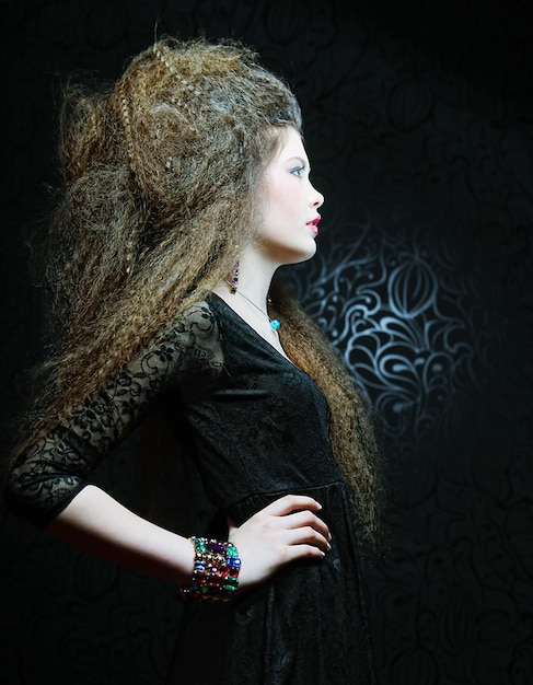 High fashion model in zwarte jurk, met creatieve hairstyling op zwarte achtergrond