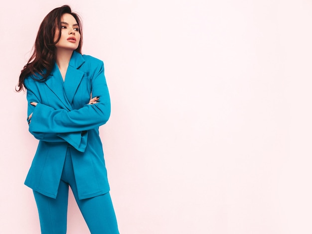 High fashion portrait of young beautiful brunette woman wearing nice trendy blue suit Sexy fashion model posing in studio Fashionable female isolated on light pink