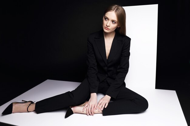 High fashion portrait of young elegant woman in black suit