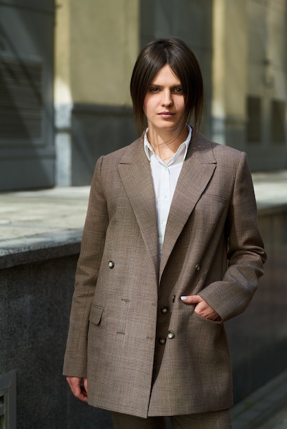 High fashion portrait of young elegant woman in brown suit walk on the street. enjoy summer lights. Fashion photo