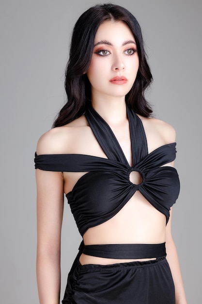 High fashion van zelfverzekerde jonge elegante vrouw, gekleed in trendy zwarte sexy jurk met perfect lichaam poseren op witte achtergrond lege ruimte kopiëren make-up