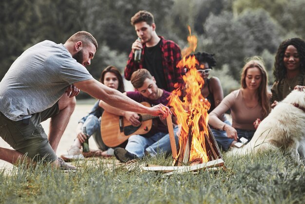 High fire. Group of people have picnic on the beach. Friends have fun at weekend time.