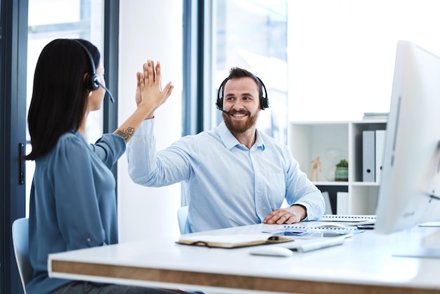 Foto batti cinque team di callcenter e contattaci telefonata successo e persone festeggiano in ufficio crm comunicazione e solidarietà nel servizio clienti uomo e donna consulente help desk con motivazione