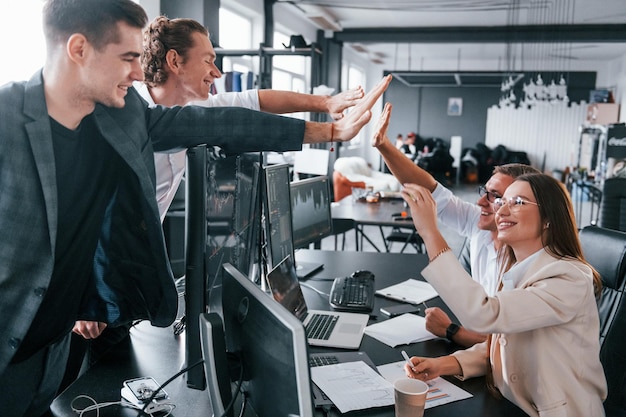 High five geven Team van effectenmakelaars werkt in een modern kantoor met veel beeldschermen