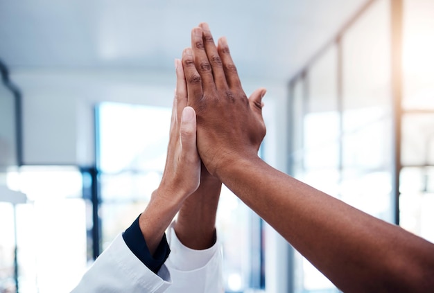high five success and doctors celebrating teamwork medical collaboration and support in a hospital closeup of healthcare hands joining in a huddle for winning achievement motivation and victory