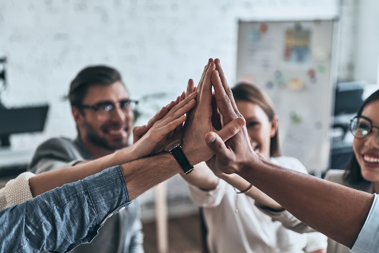 Photo high-five! top view of business colleagues giving each other high-five in a symbol of unity and smiling while working in the board room