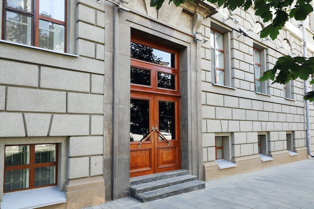 High front door of concrete building with windows from city street sidewalk