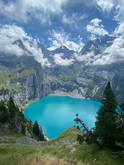 high mountain landscape with blue lake, pine trees and clouds.