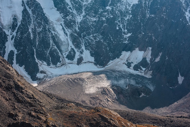 写真 雪と日光の高い山壁 氷河のクレーク 氷河のクレーク 太陽の光のクレーク 雪の山の自然背景 秋の色が山の岩に消える