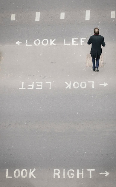 Фото Высокий перспективный вид единственного неопознанного пешехода в лондонском сити, пересекающего улицу знаковые знаки «взгляни налево» и «посмотри направо», нарисованные, чтобы помочь туристам определить направление движения