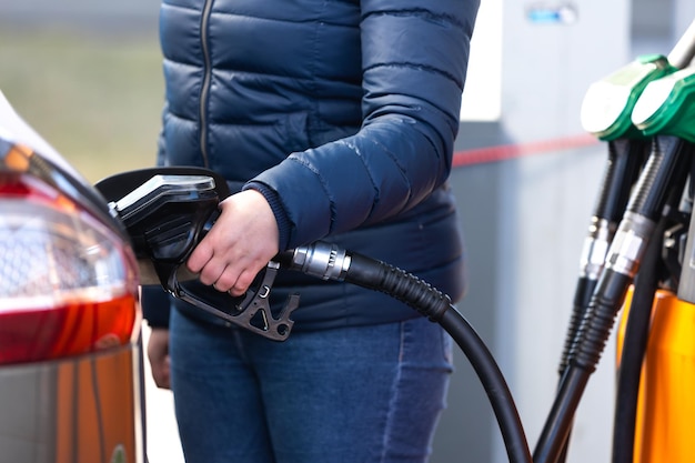 Prezzi elevati di benzina e gasolio alla stazione di servizio giovane donna che fa rifornimento economico all'auto