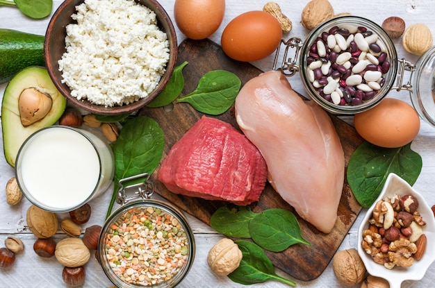 Foto alimenti ad alto contenuto proteico: pollo, carne, spinaci, noci, uova, fagioli e formaggio.