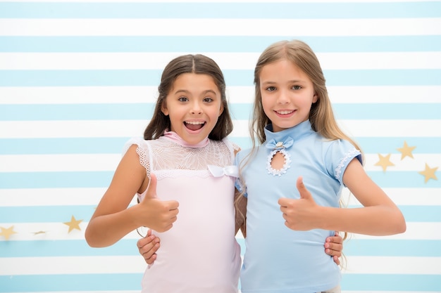 High quality. little girls show thumbs ups as symbol of high quality. success. little girls are best friends.