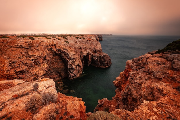 Высокие красные скалы вокруг мыса Сан-Висенте на юго-западе Португалии, в регионе Алгарве.