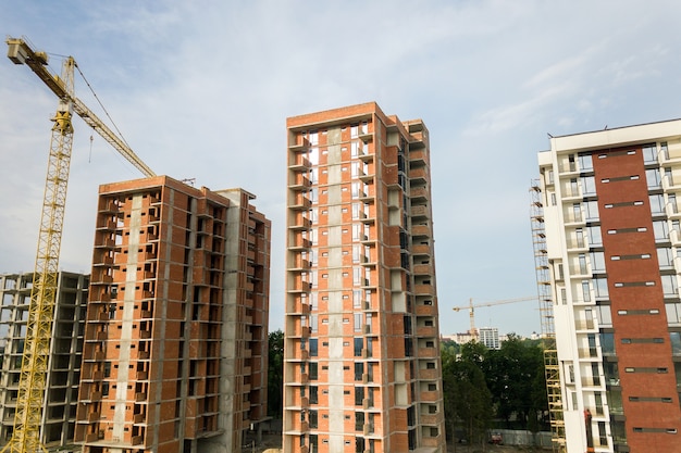 High-rise residential apartment buildings and tower crane under development on construction site. Real estate development.