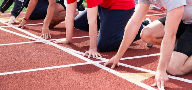 Foto ragazzi delle scuole superiori seguono i corridori alla linea di partenza pronti per iniziare una gara di sprint