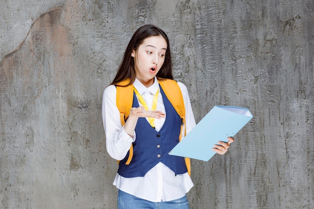 High school girl with yellow backpack and folder pointing. High quality photo