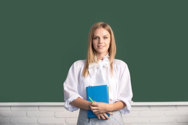 High school student holding book near blackboard learning\
english or mathematics in class