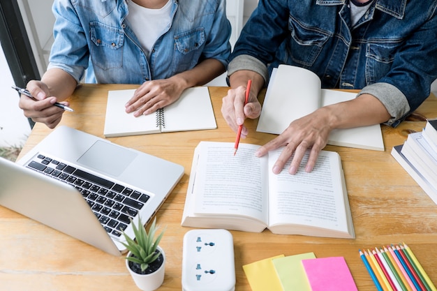 High school students or classmates group tutor in library studying and reading with helps friend doing homework