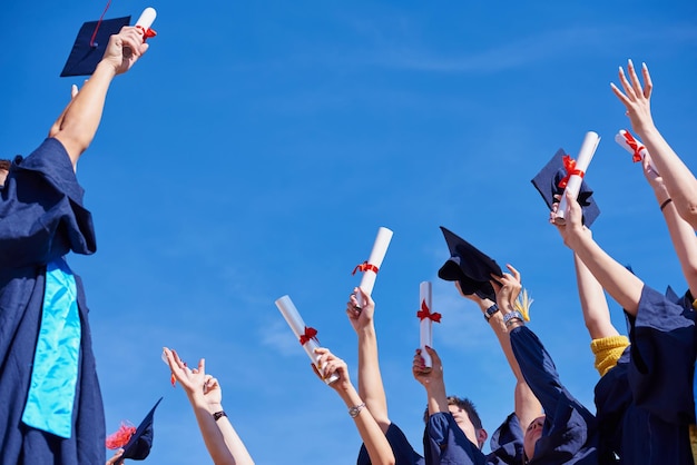 High school students graduates tossing up hats over blue sky