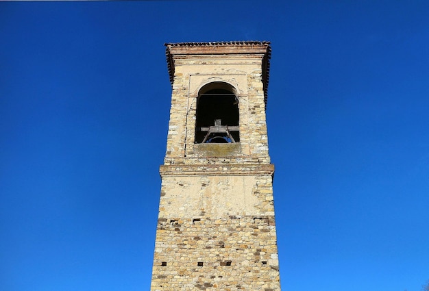 High section of bell tower against clear blue sky