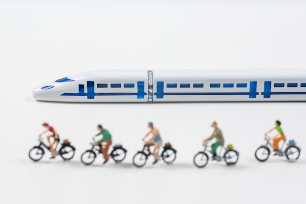 high speed train model and miniature people riding a bike