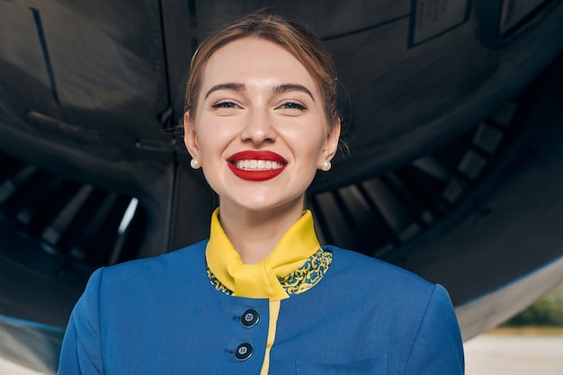 high-spirited young modern Caucasian stewardess in uniform smiling at the camera