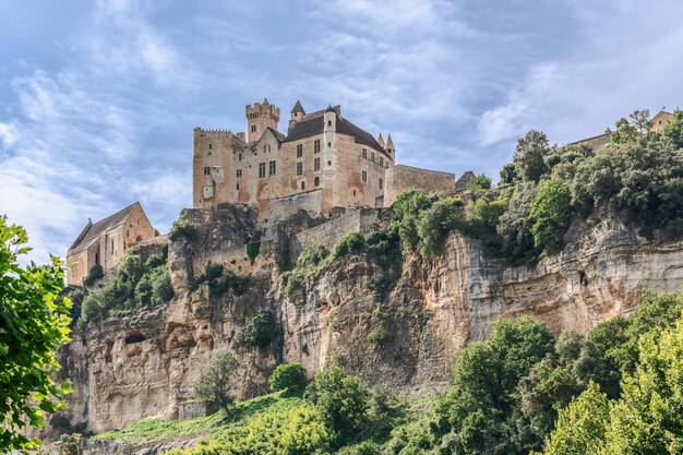 High steep rocky bank of Dordogne River and medieval castle Chateau de Beynac France