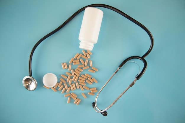 High stethoscope and pills view on blue background