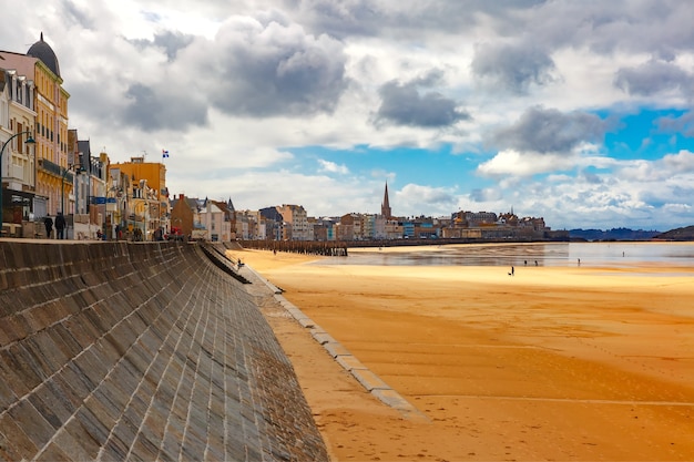 High stone embankment and beach at low tide, in beautiful walled port city of Privateers Saint-Malo, also known as city corsaire, Brittany, France