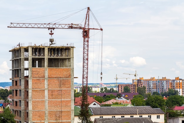 High storey building under construction with tower crane and workers men