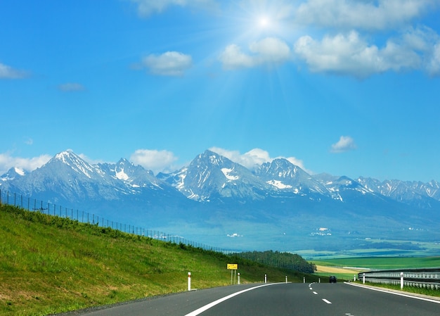 Высокие Татры, весенний солнечный вид со снегом на склоне горы и шоссе (Словакия)