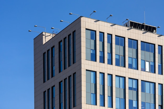 High-tech office building with transparent walls reflecting a bright blue sky with clouds. Modern architecture. Abstract glass background