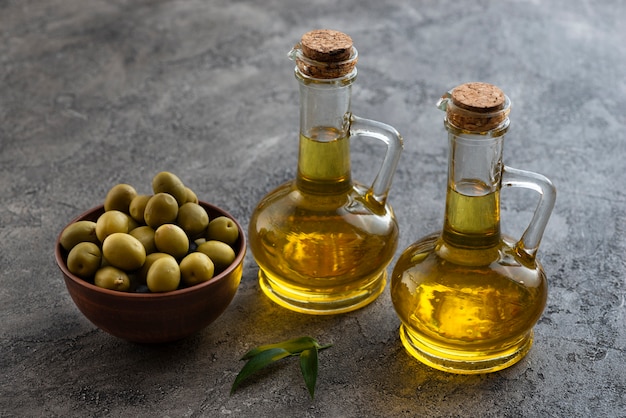 Alta vista di graziose bottiglie di olio d'oliva e ciotola di olive