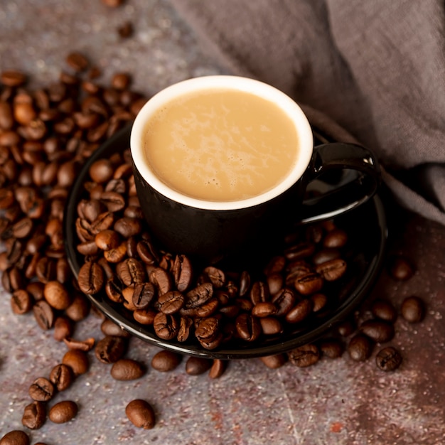 High view flavorful cup surrounded by coffee beans