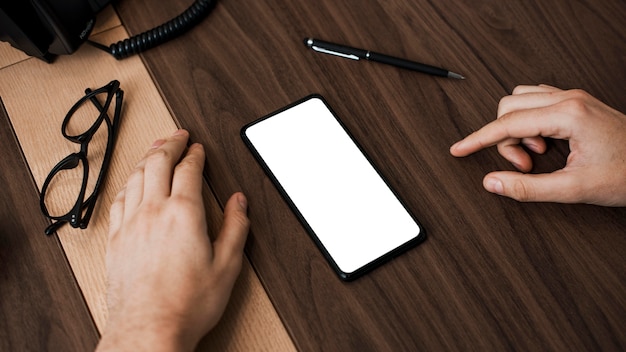 Photo high view mobile phone and reading glasses on desk