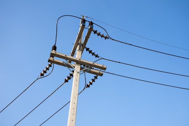 High voltage cables with electrical insulator and equipment on concrete electric pole.