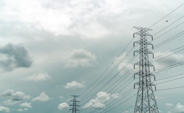 灰色の空と白い雲のある高圧送電鉄塔と電線。電柱。電力とエネルギーの概念。ワイヤーケーブル付きの高電圧グリッドタワー。インフラ。配電