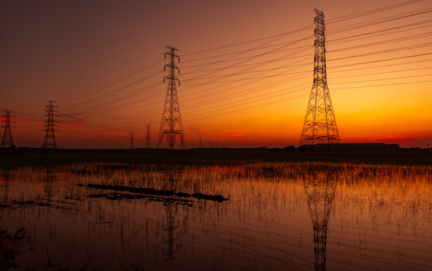 High voltage electric pylon and electrical wire with sunset sky