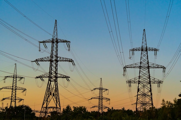 Torre elettrica ad alta tensione silhouette sui tralicci dell'ora del tramonto sullo sfondo dell'ora del tramonto messa a fuoco selettiva