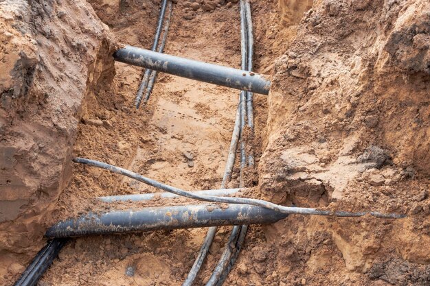 The high voltage electrical cable is laid in a trench under existing engineering sewerage networks Laying a high voltage cable for supplying buildings with electricity