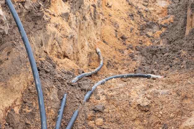 The high voltage electrical cable is laid in a trench under existing engineering sewerage networks Laying a high voltage cable for supplying buildings with electricity