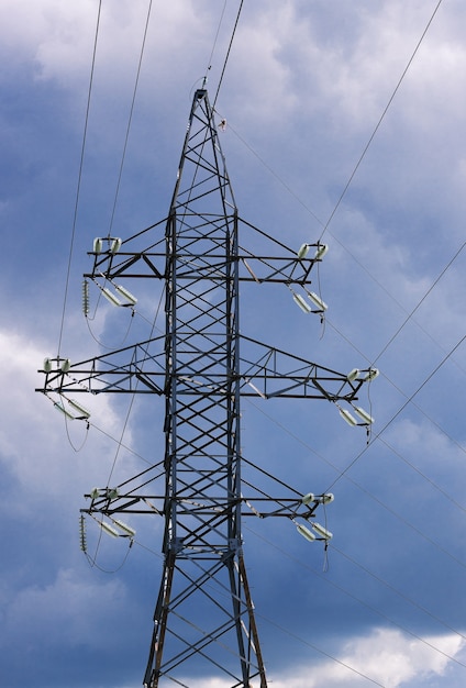 濃い青の雲の空の背景にケーブル付き高電圧ポストまたは高電圧タワー