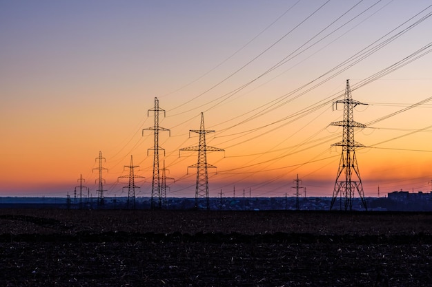 Photo high voltage power line in a field at sunset