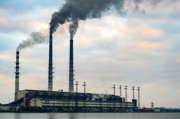 High voltage power lines and coal power plant pipes with black
smoke moving up polluting atmosphere.