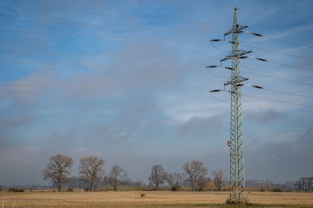 High voltage power lines through fields and meadows they supply power to towns and villages