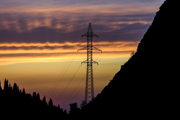 High voltage power pylon in the mountains at sunset Cloudy sky Mountain background