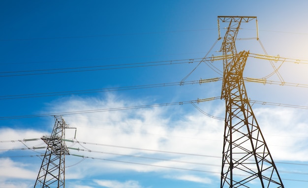 A high voltage power pylons against blue cloudy sky