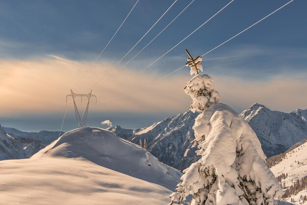 High voltage pylons on snowy mountains transpose electricity